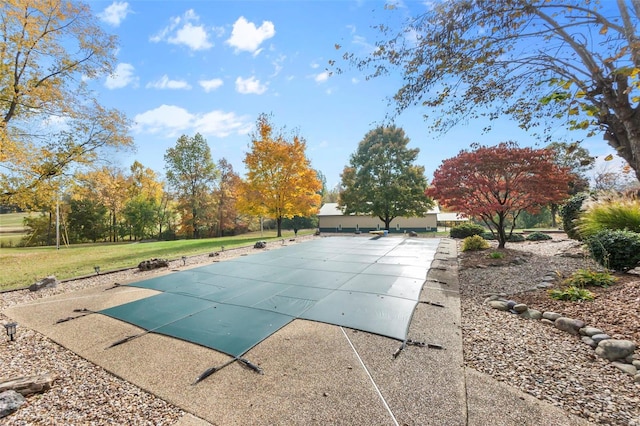 view of pool featuring a lawn, a covered pool, and a patio area