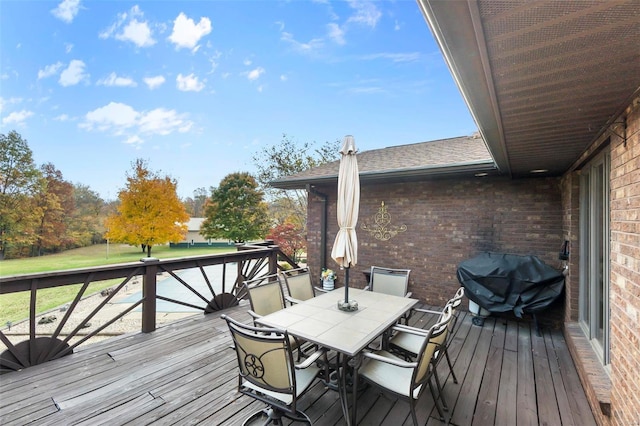 wooden terrace with a lawn and outdoor dining area
