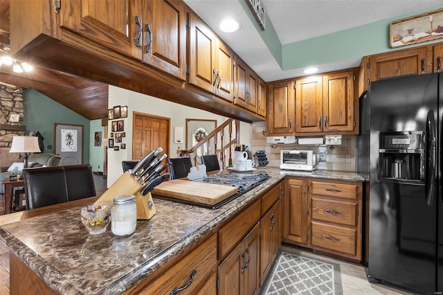 kitchen featuring backsplash, black fridge, a textured ceiling, dark stone counters, and vaulted ceiling