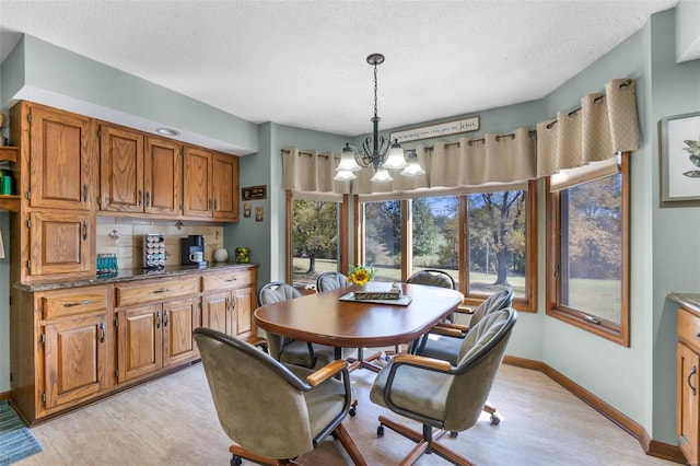 dining room with a chandelier, light wood-type flooring, and a textured ceiling