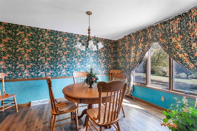 dining room with an inviting chandelier, wood finished floors, wallpapered walls, and baseboards