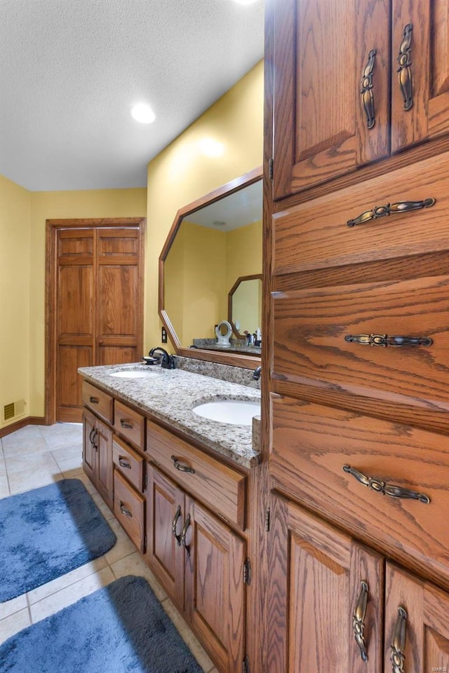 bathroom with vanity, a textured ceiling, and tile patterned flooring