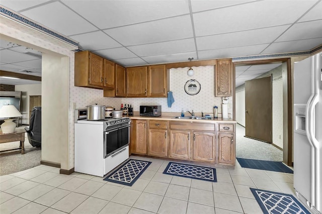 kitchen with white appliances, a drop ceiling, light colored carpet, and sink