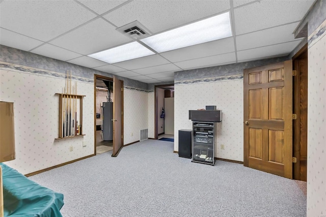 finished basement with water heater, visible vents, a paneled ceiling, and wallpapered walls
