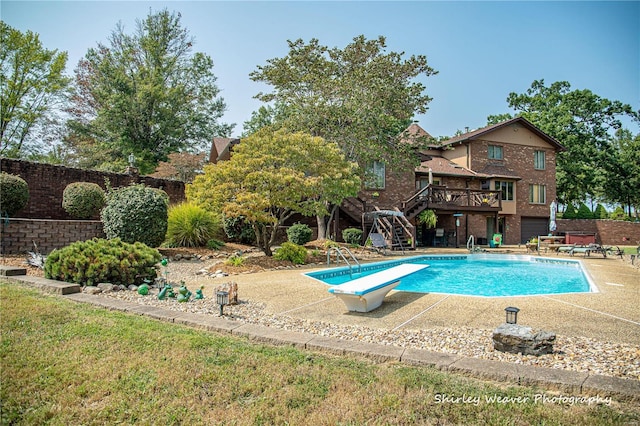 view of pool featuring a wooden deck, a patio, and a diving board