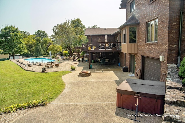 exterior space featuring a deck, an outdoor fire pit, a patio, a garage, and an outdoor pool