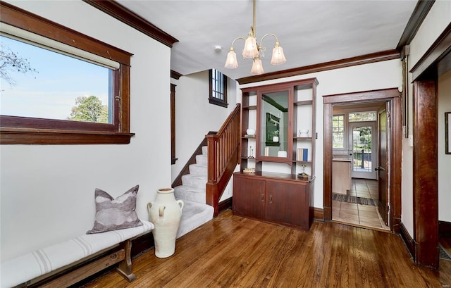 interior space with ornamental molding, an inviting chandelier, and hardwood / wood-style floors