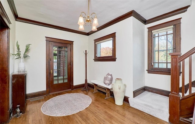 foyer entrance with hardwood / wood-style floors, crown molding, and an inviting chandelier