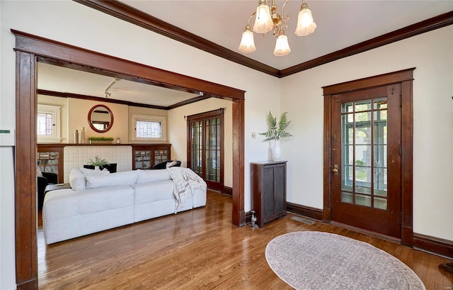 entryway with hardwood / wood-style flooring, ornamental molding, and an inviting chandelier