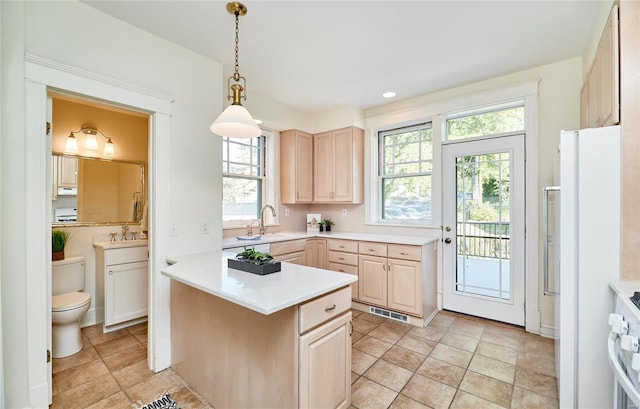 kitchen featuring light brown cabinets, white appliances, kitchen peninsula, and pendant lighting