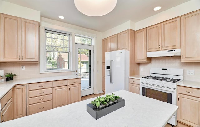 kitchen featuring light brown cabinetry, white appliances, and tasteful backsplash