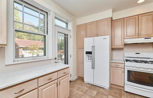 kitchen with a healthy amount of sunlight, decorative backsplash, light brown cabinetry, and white appliances