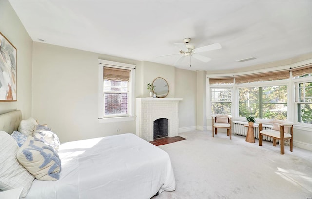 carpeted bedroom featuring a fireplace, multiple windows, and ceiling fan