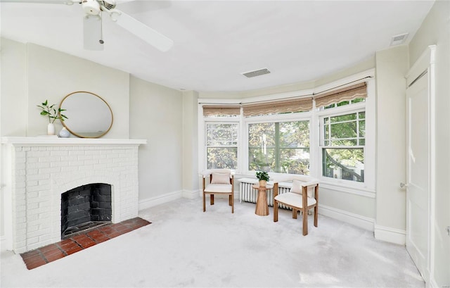 living area featuring ceiling fan, carpet flooring, and a fireplace