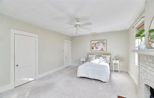 bedroom featuring light carpet, a brick fireplace, and ceiling fan