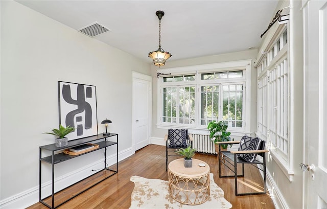 sitting room with hardwood / wood-style floors and radiator heating unit