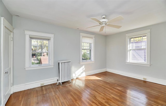 spare room featuring hardwood / wood-style floors, ceiling fan, and radiator