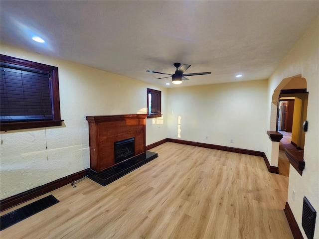 living room with a fireplace, light hardwood / wood-style flooring, and ceiling fan