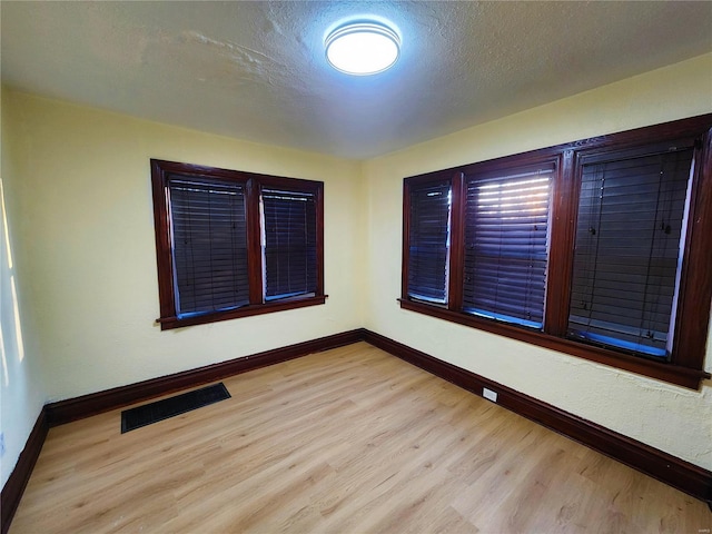 unfurnished room featuring a textured ceiling and light hardwood / wood-style floors