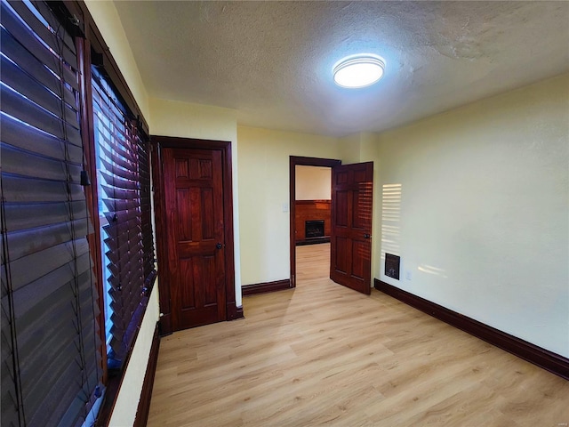 unfurnished bedroom featuring a fireplace, light wood-type flooring, and a textured ceiling