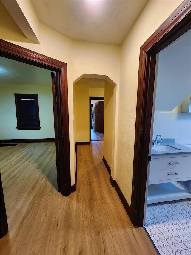 corridor featuring sink and light hardwood / wood-style flooring