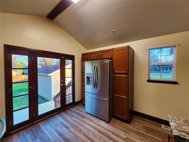 kitchen featuring stainless steel fridge with ice dispenser, french doors, light stone counters, and light wood-type flooring