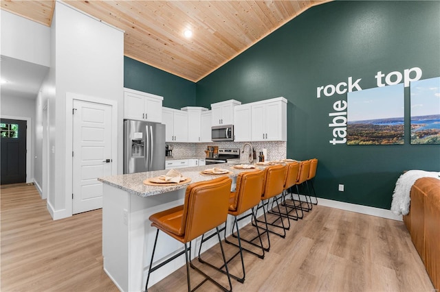 kitchen with white cabinetry, high vaulted ceiling, stainless steel appliances, and a breakfast bar