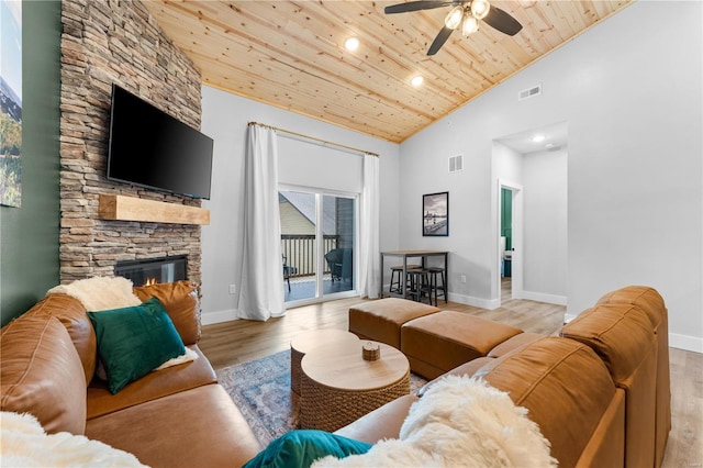 living room with a stone fireplace, light hardwood / wood-style floors, ceiling fan, wooden ceiling, and high vaulted ceiling