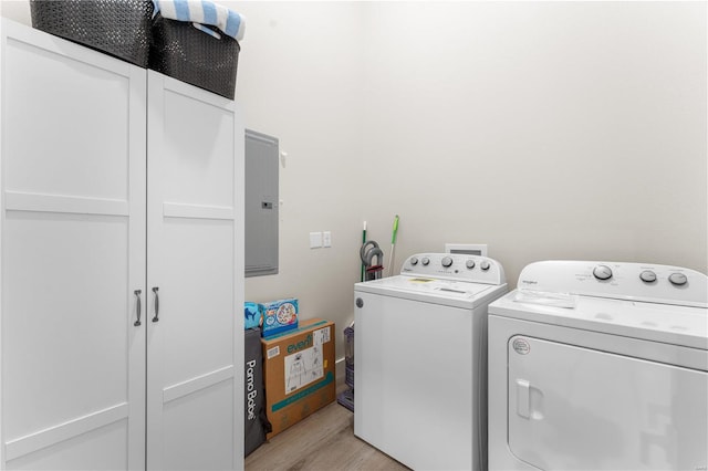 washroom featuring electric panel, light hardwood / wood-style floors, separate washer and dryer, and cabinets