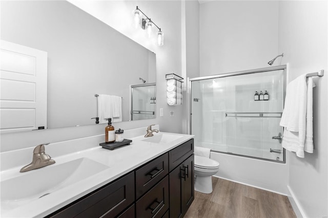 full bathroom with toilet, vanity, wood-type flooring, and shower / bath combination with glass door