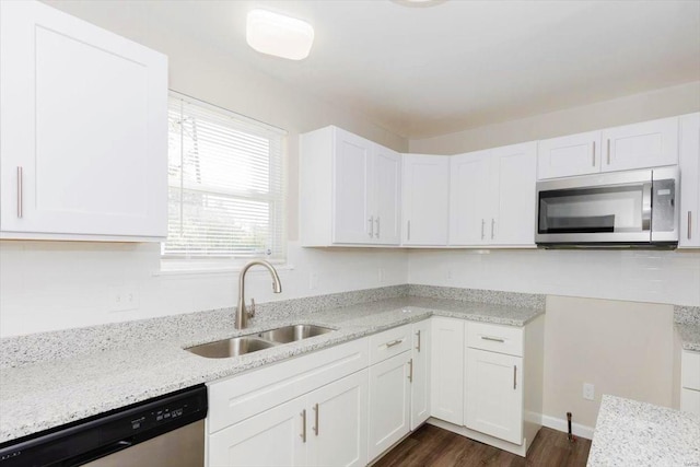 kitchen with white cabinets, dark hardwood / wood-style flooring, appliances with stainless steel finishes, light stone countertops, and sink