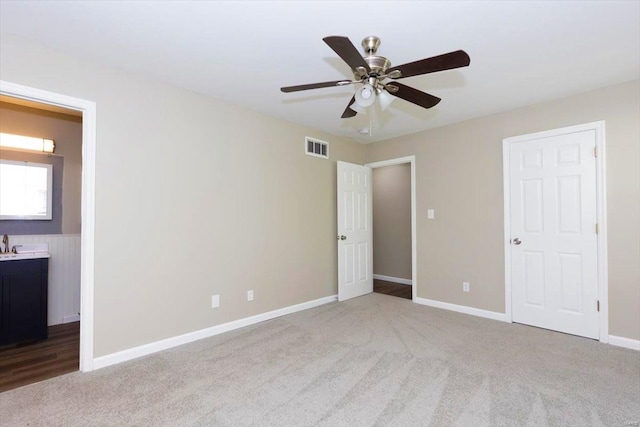 unfurnished bedroom with connected bathroom, light carpet, and ceiling fan