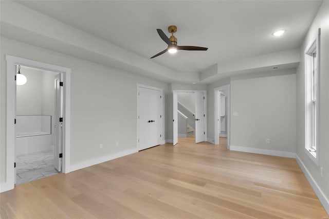 unfurnished bedroom with ensuite bathroom, light wood-type flooring, and ceiling fan