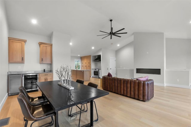 dining room with ceiling fan, vaulted ceiling, light hardwood / wood-style flooring, and beverage cooler