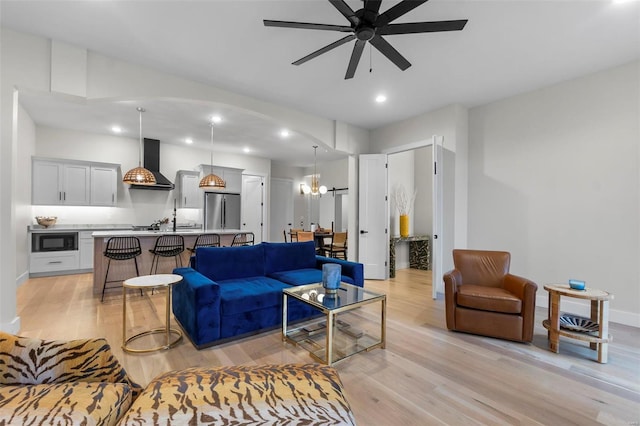 living room featuring light hardwood / wood-style flooring and ceiling fan with notable chandelier