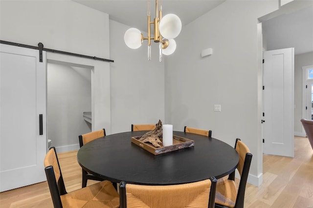 dining room featuring light hardwood / wood-style floors, a notable chandelier, and a barn door