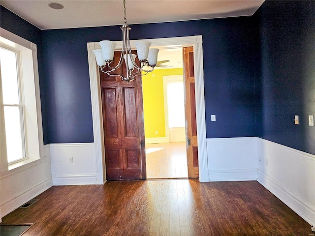 spare room featuring a healthy amount of sunlight, dark hardwood / wood-style flooring, and a chandelier