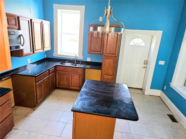 kitchen with light tile patterned flooring, a center island, sink, and a notable chandelier