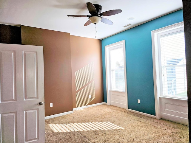 empty room featuring ceiling fan, carpet flooring, and plenty of natural light