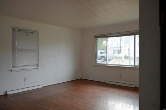 spare room with wood-type flooring and a baseboard heating unit