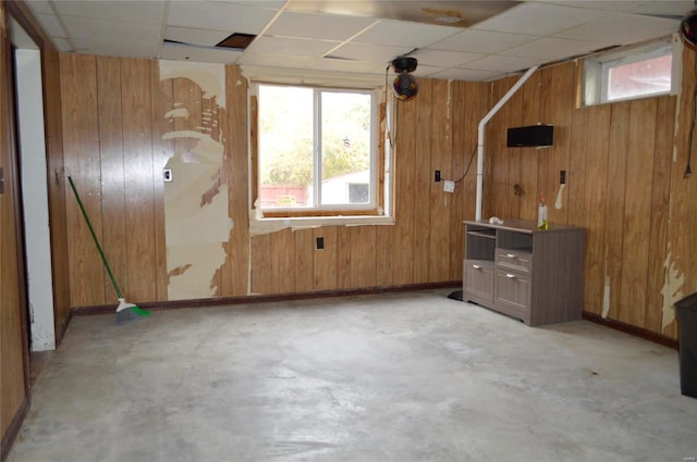 interior space with a paneled ceiling and wood walls