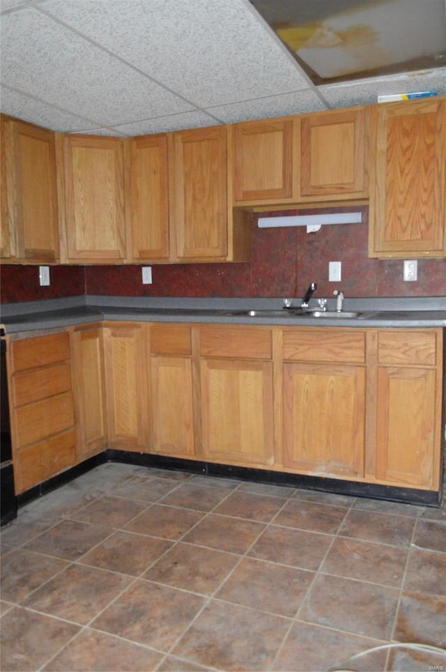 kitchen featuring decorative backsplash, a drop ceiling, dark tile patterned floors, and sink