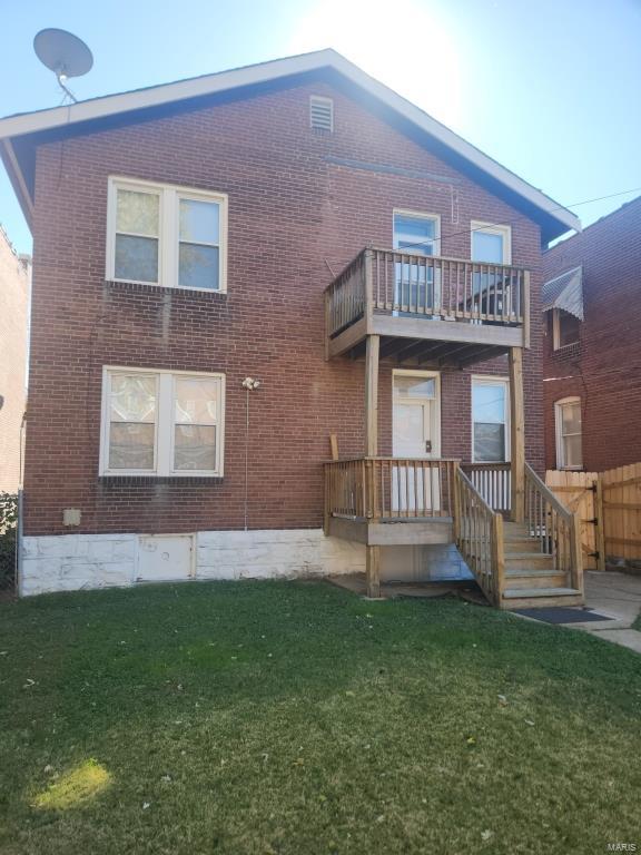 back of property with a yard and a balcony