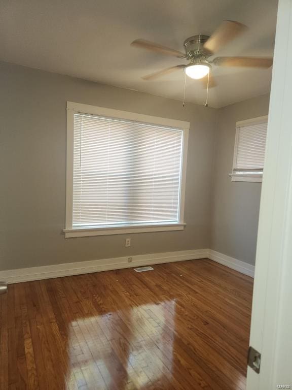 empty room featuring wood-type flooring, a healthy amount of sunlight, and ceiling fan