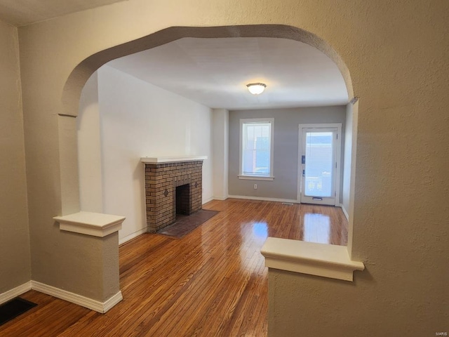 unfurnished living room with hardwood / wood-style floors and a brick fireplace