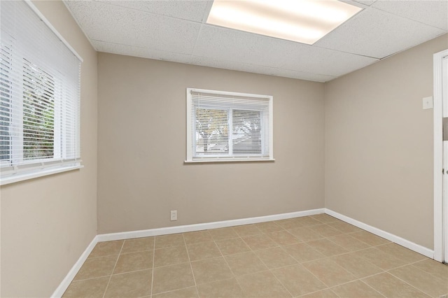 unfurnished room with a paneled ceiling and light tile patterned floors