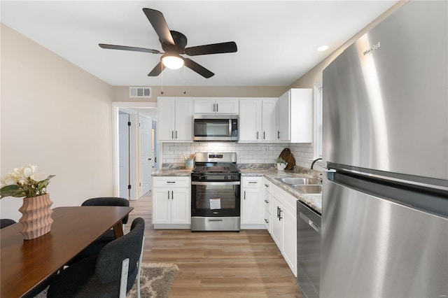 kitchen with white cabinets, sink, appliances with stainless steel finishes, and light hardwood / wood-style flooring