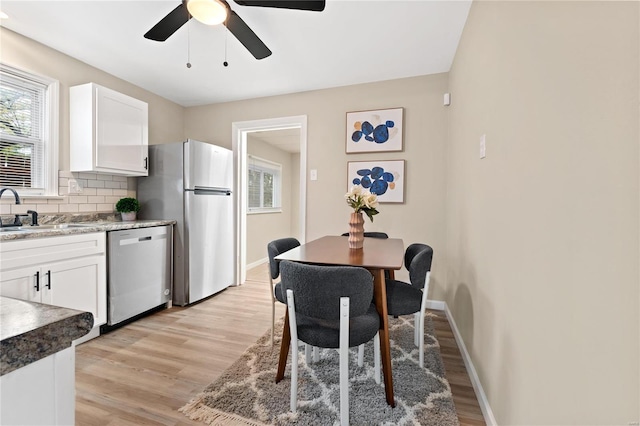 kitchen featuring backsplash, sink, light hardwood / wood-style flooring, appliances with stainless steel finishes, and white cabinetry