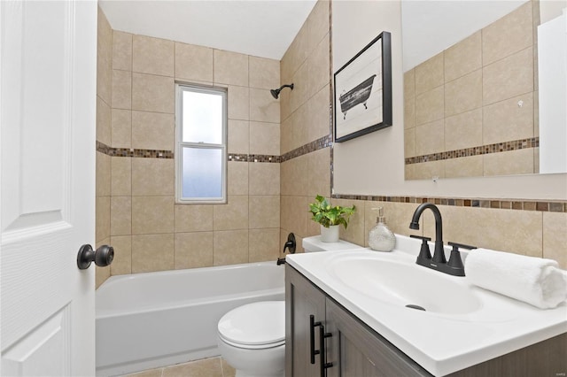 full bathroom featuring vanity, tile patterned floors, tiled shower / bath combo, toilet, and tile walls