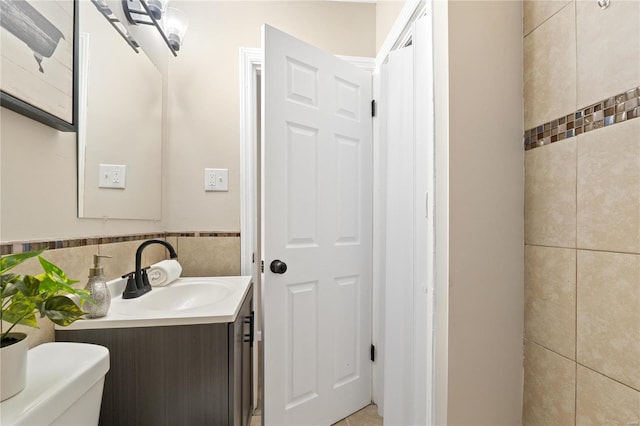 bathroom with vanity, tile walls, and toilet